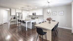 Una cocina amplia con una isla central, electrodomésticos de acero inoxidable y un comedor con mesa y sillas de madera.