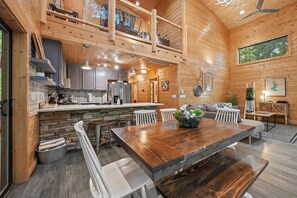 A spacious wooden cabin interior with a kitchen, dining area, and a cozy seating space.