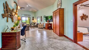 A spacious living area with a large wooden cabinet, a ceiling fan, and a television. - Stunning Lake  & Volcano Views (Tronadora)