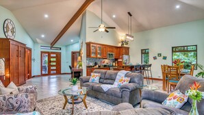 A spacious living room with a gray sofa, a coffee table, and a dining area with wooden chairs and a glass table. - Stunning Lake  & Volcano Views (Tronadora)