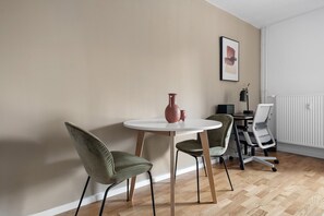 Ein moderner Raum mit einem runden Tisch, zwei Stühlen, einer Vase, einem gerahmten Bild und einer Heizung.