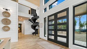 Un intérieur spacieux agrémenté d’un escalier en colimaçon, d’une grande porte coulissante et offrant une vue sur l’extérieur.