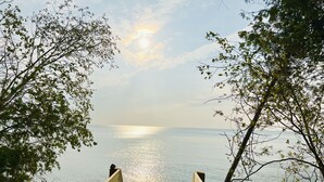 Een houten terras dat naar een strand leidt, met een helder uitzicht op de oceaan en een stralende zon aan de hemel.