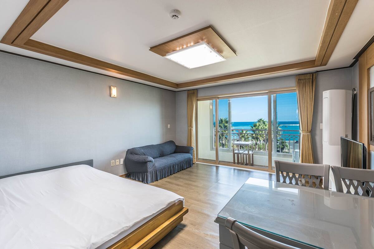 Une chambre d’hôtel avec un lit, un canapé, une table à manger et une vue sur l’océan.