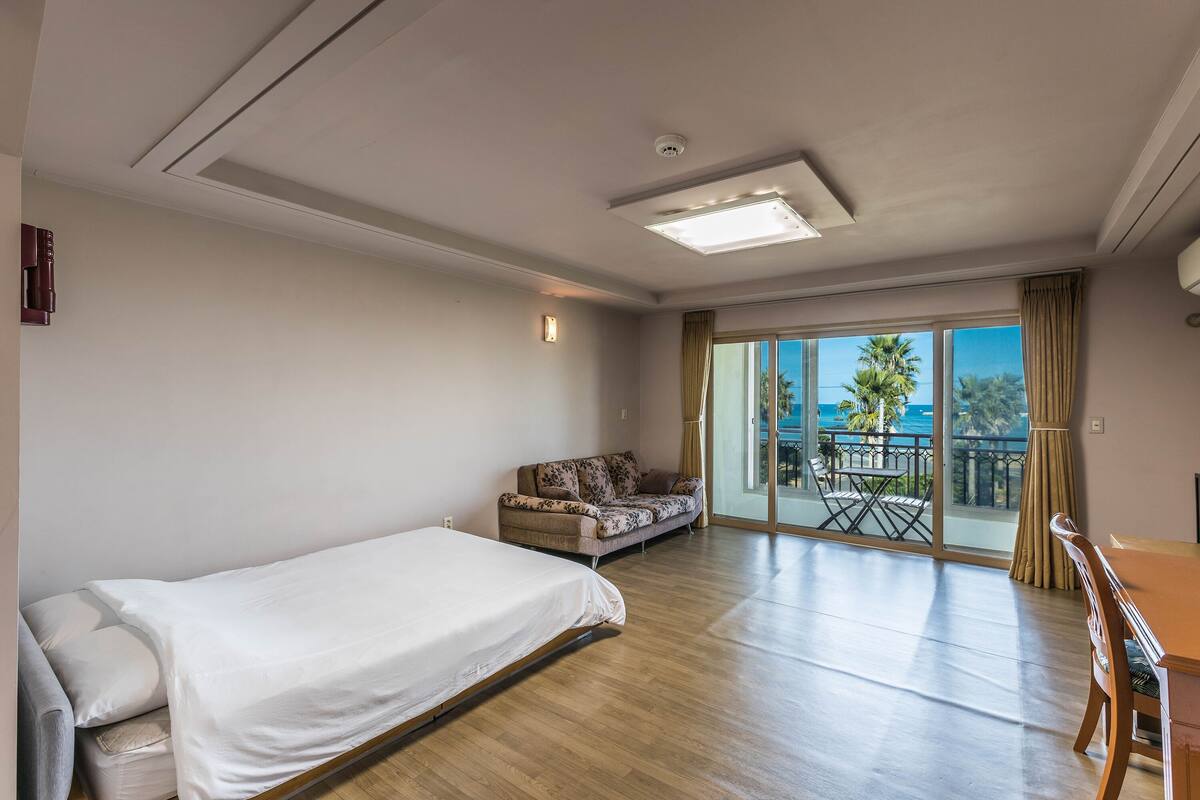Une chambre d’hôtel comprenant un lit, un canapé, une table à manger et un balcon avec vue sur l’océan.