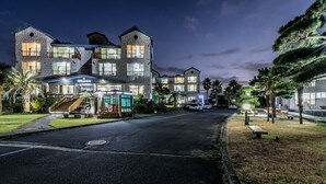 Un hotel de varios pisos con fachada de piedra, mobiliario exterior y una entrada bien iluminada.