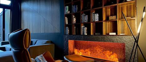 A modern living room with a fireplace, a bookshelf, and a comfortable seating area.