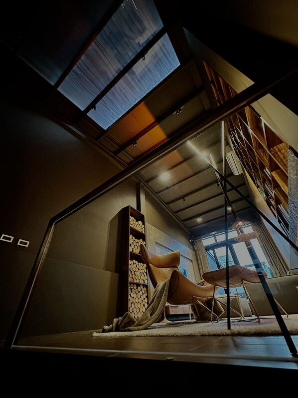 A modern interior with a sloped ceiling, a built-in wooden shelf, and a seating area with a cushioned chair and a small table. - HERE Hostel - Pingtung (Pingtung)