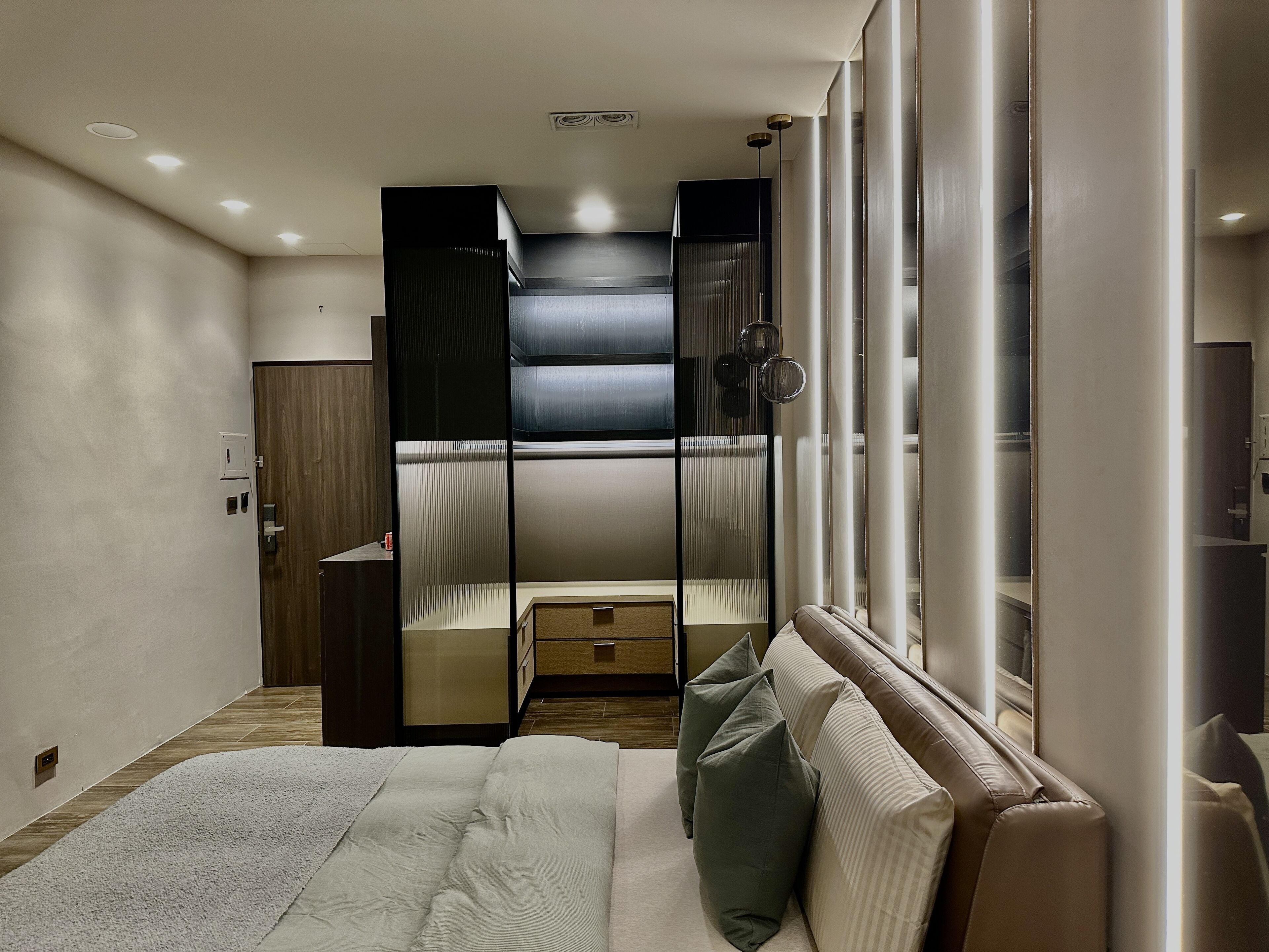 A modern bedroom with a bed, a wardrobe, and a mirror.