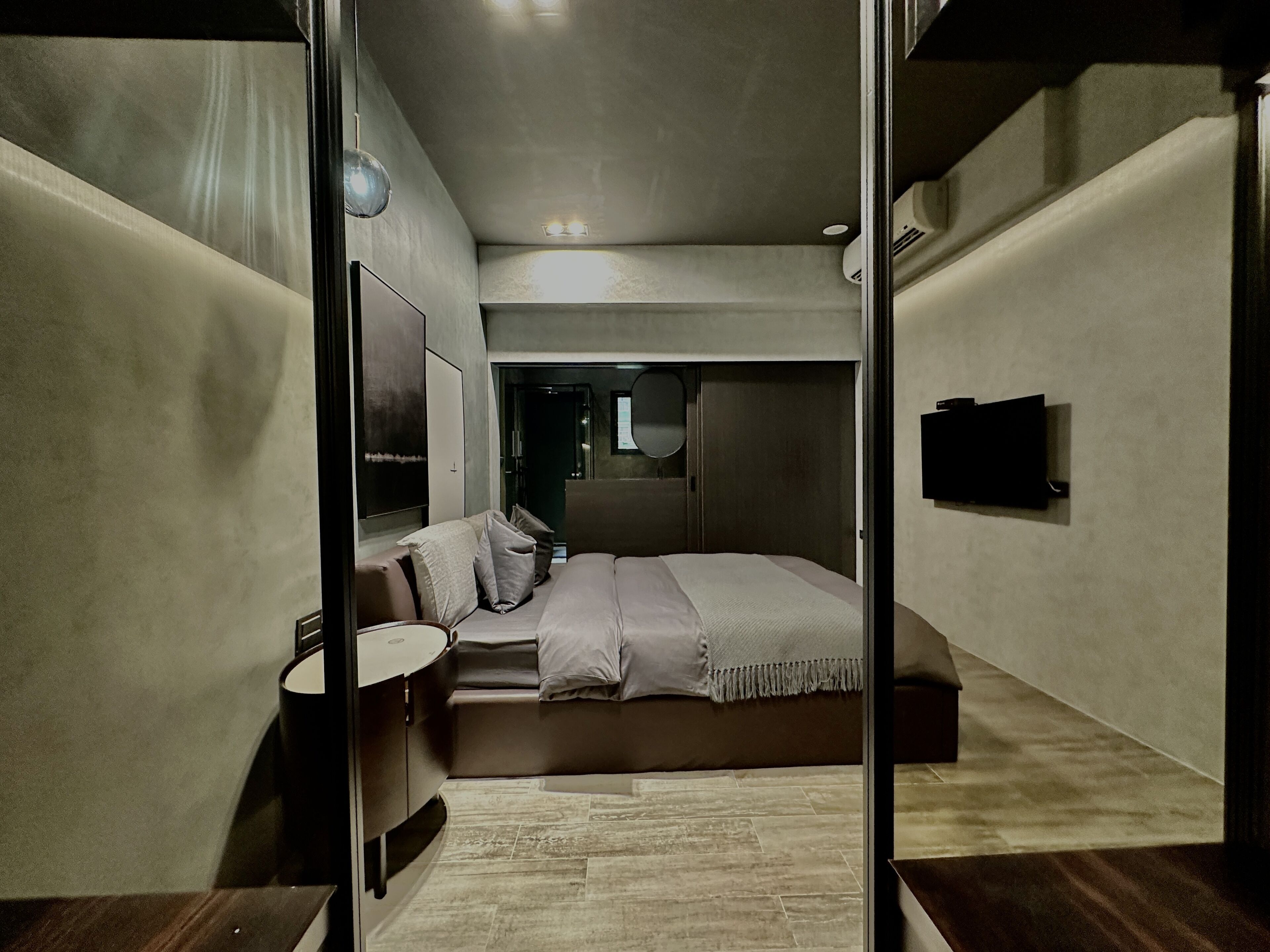 Un dormitorio moderno con cama, mesita de noche y espejo.