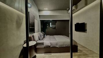 Un dormitorio moderno con cama, mesita de noche y espejo.