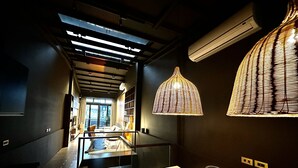 Un interior moderno con una mesa de vidrio, una lámpara de mimbre y vistas a través de un ventanal.