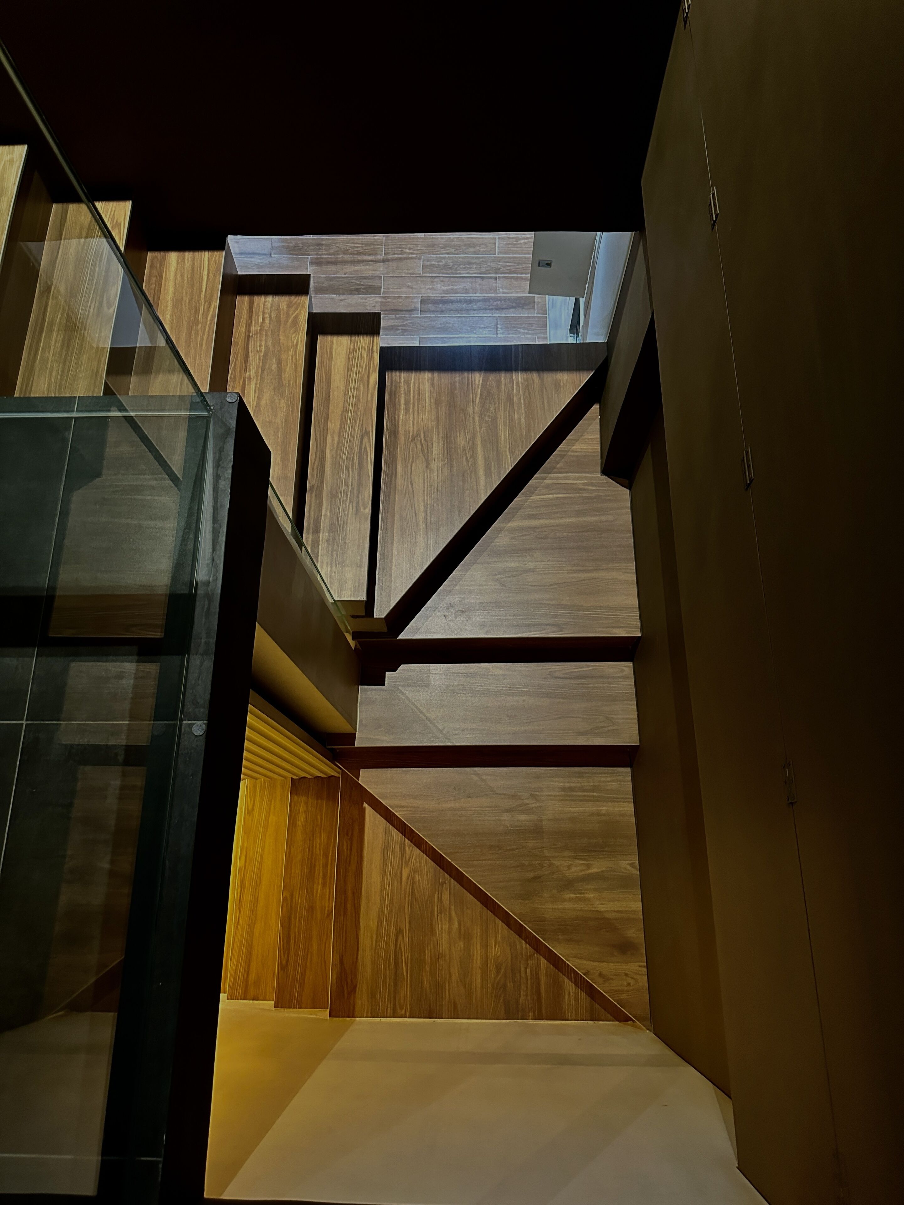 A modern interior with a staircase, wooden panels, and glass elements.