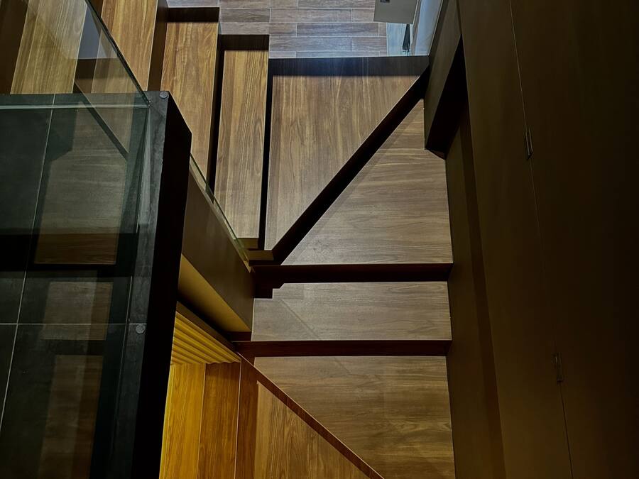 A modern interior with a staircase, wooden panels, and glass elements.