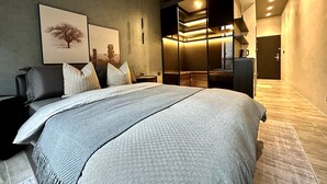 Un dormitorio moderno con una cama grande, un sofá oscuro y un vestidor con puertas correderas.