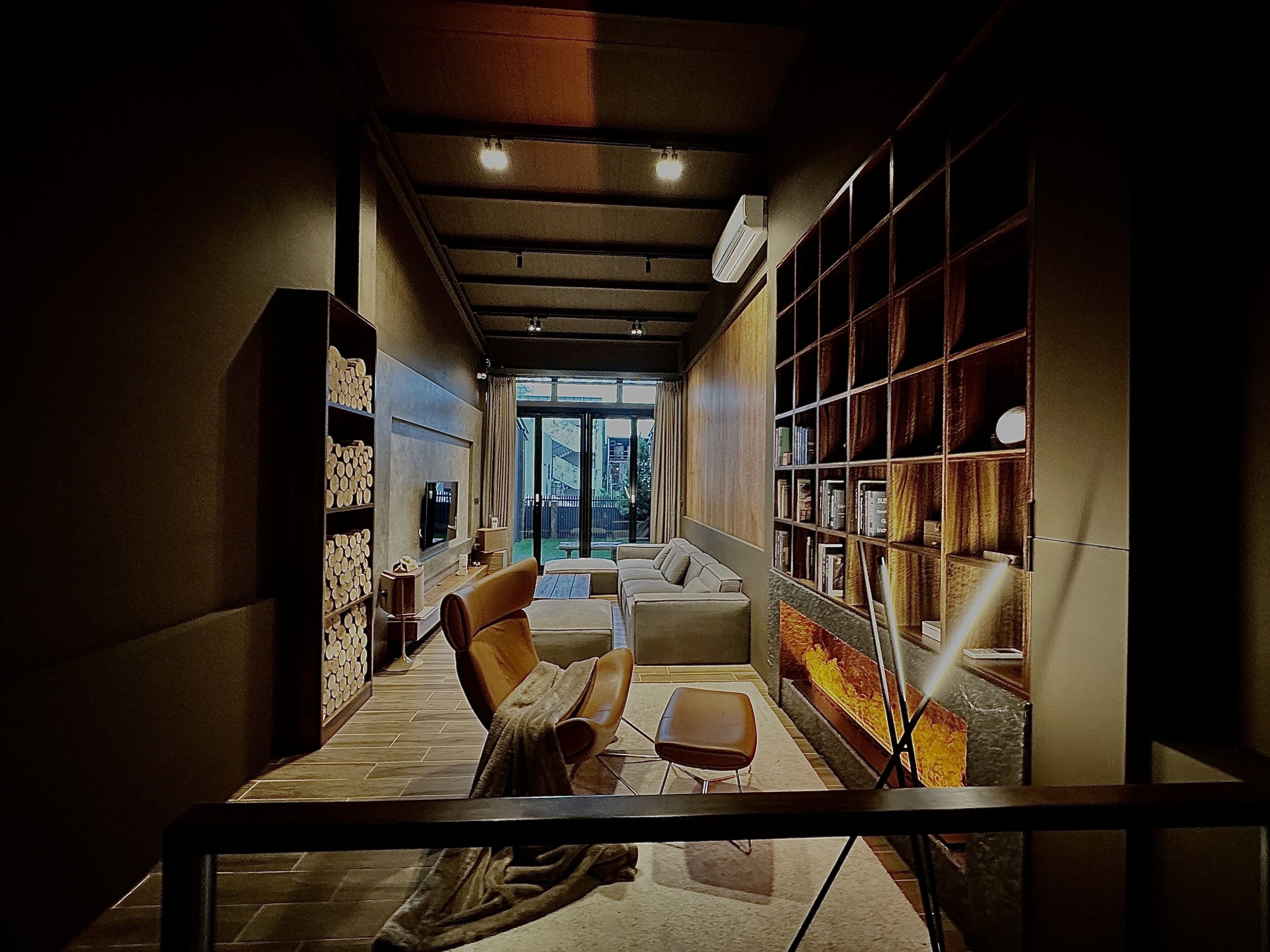 Un intérieur moderne avec un canapé, des fauteuils, une cheminée et une bibliothèque.