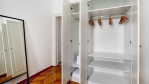 A walk-in closet with open doors, wooden hangers, and a mirrored closet door.