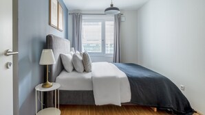 Ein Schlafzimmer mit einem Bett, einer Nachttischlampe und einem Fenster mit Jalousien.