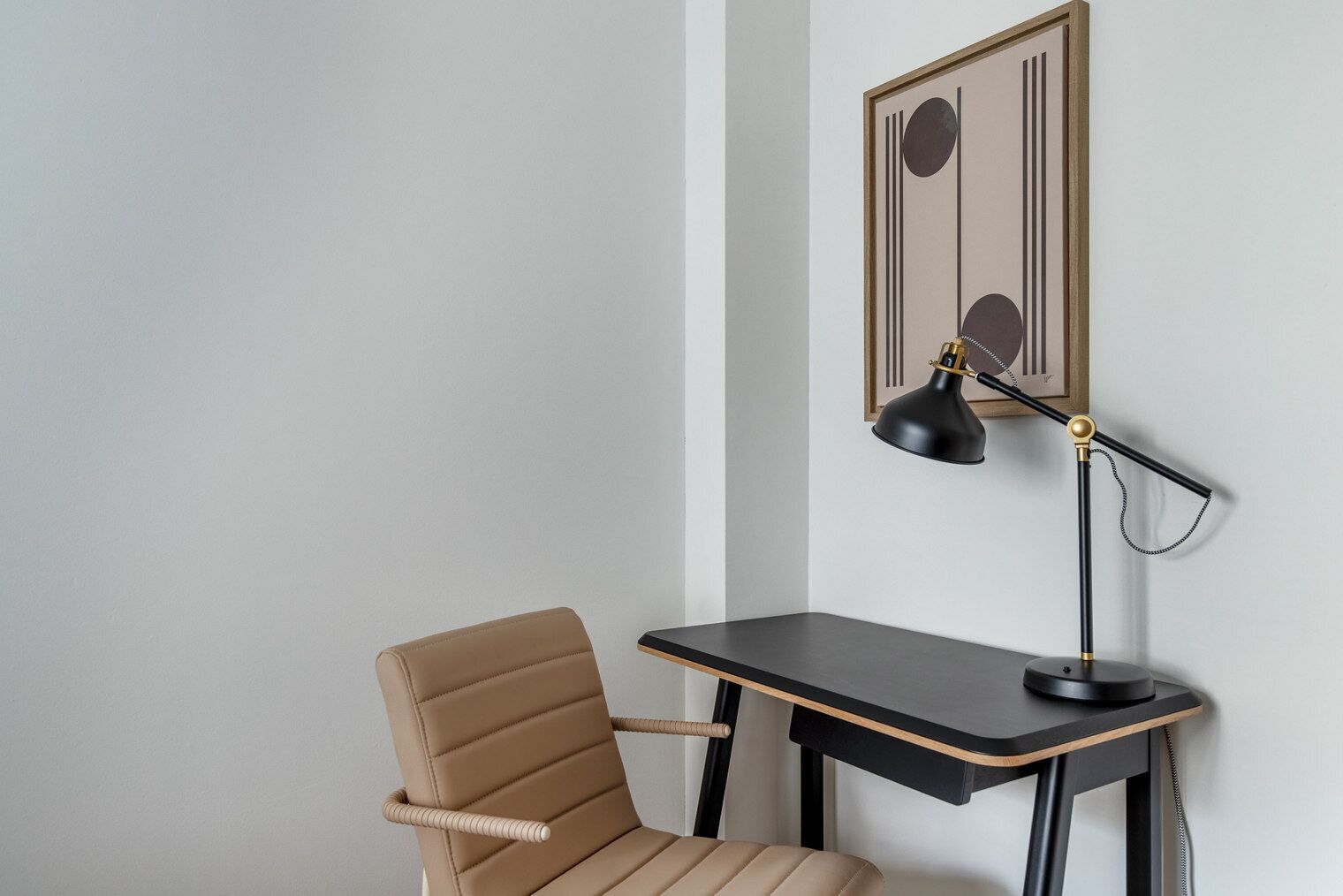 A chair and a desk with a lamp in a corner of a room.