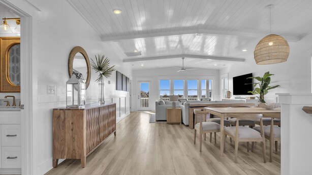 Une cuisine spacieuse dotée d’un plancher en bois, d’un îlot central et d’un coin repas avec des chaises.