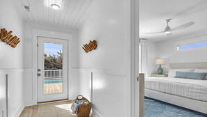 Une chambre d’hôtel moderne équipée d’un lit, d’un ventilateur de plafond, d’une table de chevet et offrant une vue sur une piscine.