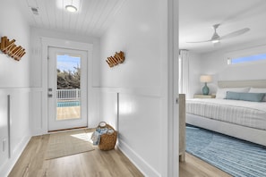 A modern hotel room with a bed, a ceiling fan, a nightstand, and a view of a pool. - Elemental: 6BD New Build Ocean View with Private Pool & Elevator (Oak Island)