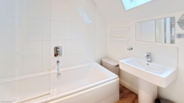 A modern bathroom with a bathtub, a sink, and a mirror.