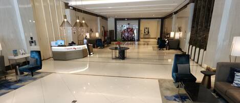 A spacious lobby with a reception desk, seating area, and a decorative wall.