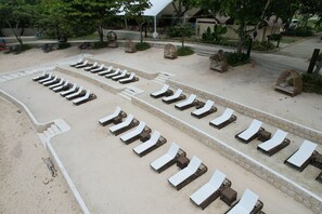 Ein Strandlounge mit Reihen von Liegestühlen und Korbmöbeln.