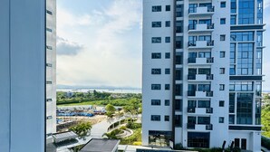 Un edificio de gran altura con piscina en la azotea y vistas a una zona ajardinada con árboles y un paisaje distante.