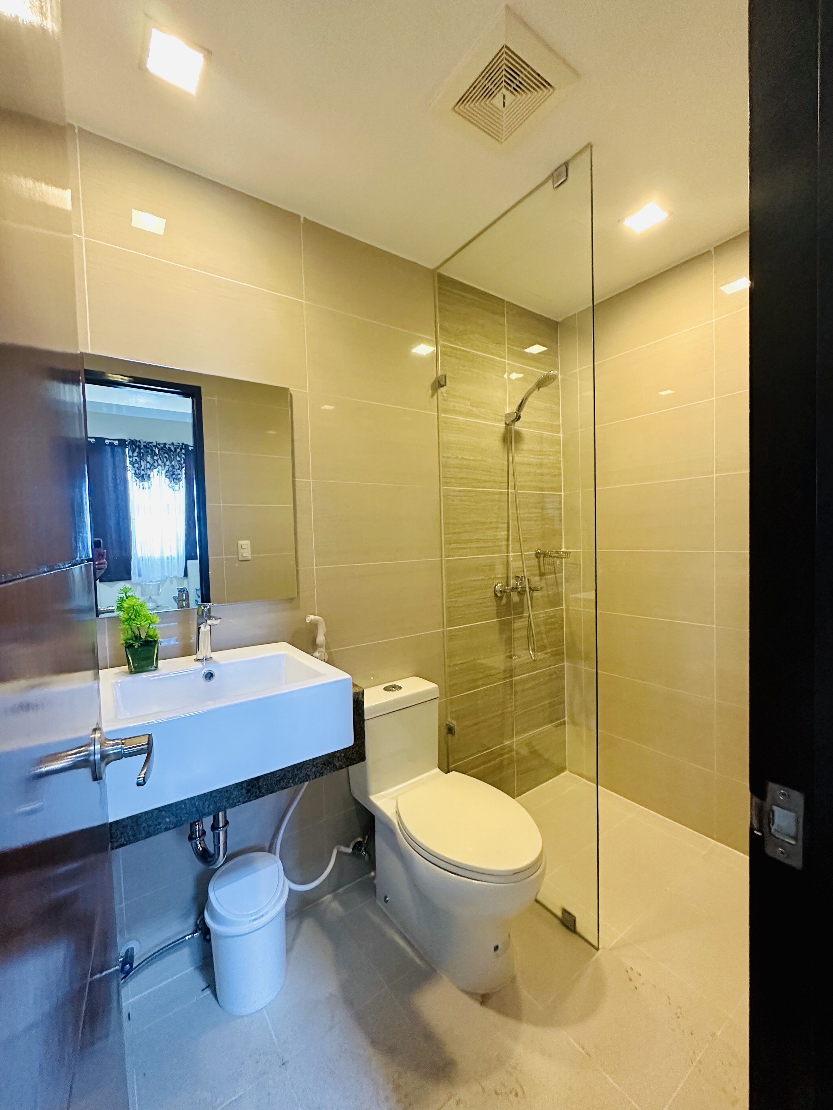 A modern bathroom with a glass-enclosed shower, a white sink with a mirror above it, and a toilet.