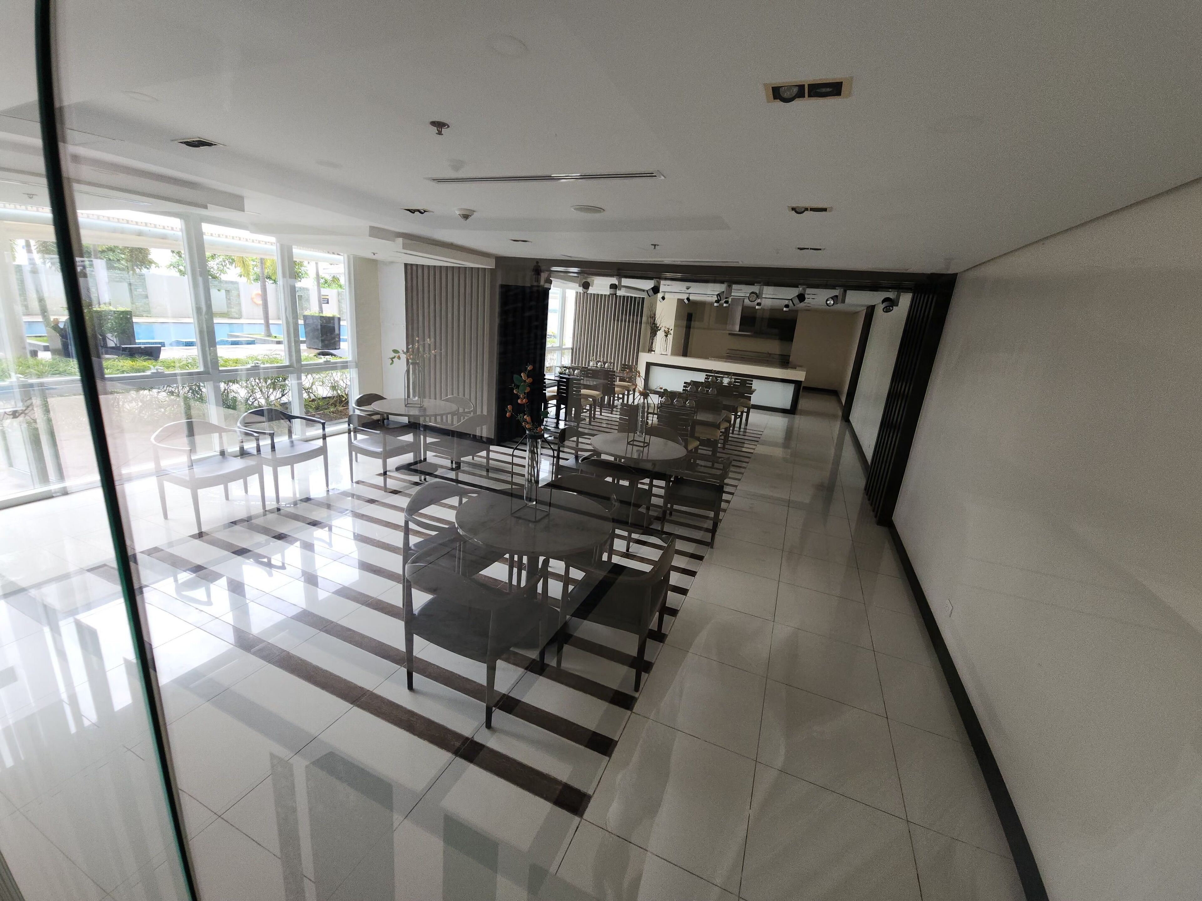 Un área de comedor moderna con divisiones de vidrio, sillas de metal y una mesa central.