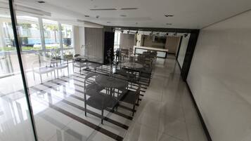 Un área de comedor moderna con divisiones de vidrio, sillas de metal y una mesa central.