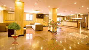 A hotel lobby with a reception desk, seating area, and potted plants. - Golden Rain 2 Hotel (Nha Trang)