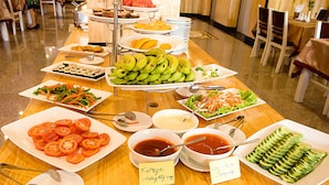 A buffet table with various food items including sliced tomatoes, cucumbers, and bowls of soup. - Golden Rain 2 Hotel (Nha Trang)