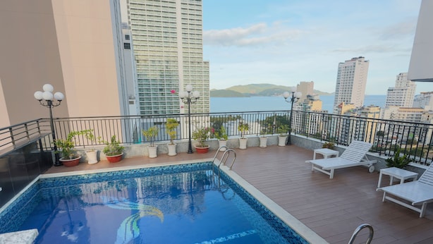 A rooftop pool with a view of the sea and surrounding buildings. - Golden Rain 2 Hotel (Nha Trang)