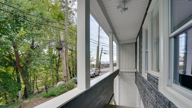 A covered outdoor corridor with a view of a road and trees. - Modern Hastings-On-Hudson Home Near River! (Hastings-On-Hudson)