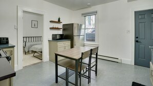 A compact kitchen with a dining table and chairs, a refrigerator, and a microwave. - Modern Hastings-On-Hudson Home Near River! (Hastings-On-Hudson)