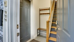 A hallway with a grey door, a metal rack, and a wooden staircase. - Modern Hastings-On-Hudson Home Near River! (Hastings-On-Hudson)