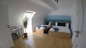 A bedroom with two beds, a desk, and a potted plant. - Triple room with ensuite bathroom (Portmagee)