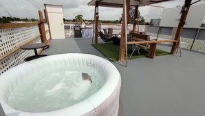 Una terraza con jacuzzi, mobiliario exterior y vistas a la ciudad.