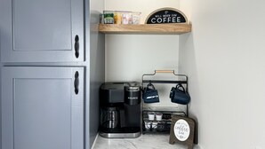 Un área de cocina con una cafetera, un soporte para tazas de café y un letrero que dice