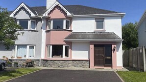 A two-story house with a stone foundation, a bay window, and a front door with a small porch. - Sunshine Heights by Interhome (Kenmare)