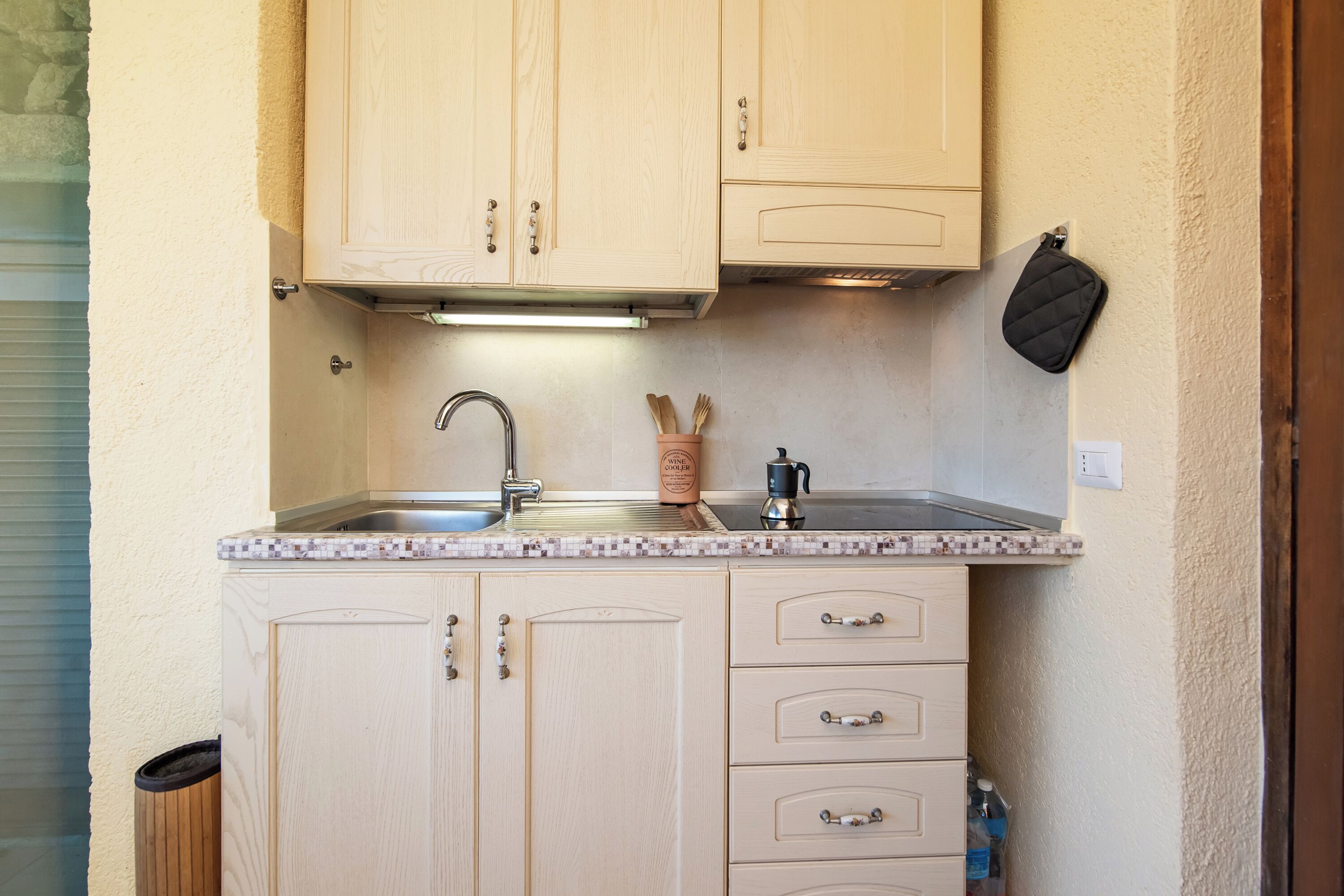 A compact kitchen with wooden cabinets, a stainless steel sink, and a countertop.