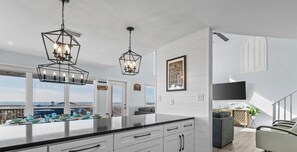 A modern kitchen with white cabinetry, a large island, and pendant lighting.