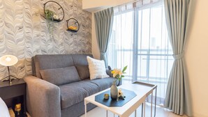 Ein modernes Wohnzimmer mit einem grauen Sofa, einem weißen Tisch und einer Vase mit Blumen.