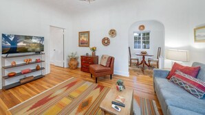 Un salon comprenant un téléviseur, un canapé, une table basse et un coin repas avec une table et des chaises.