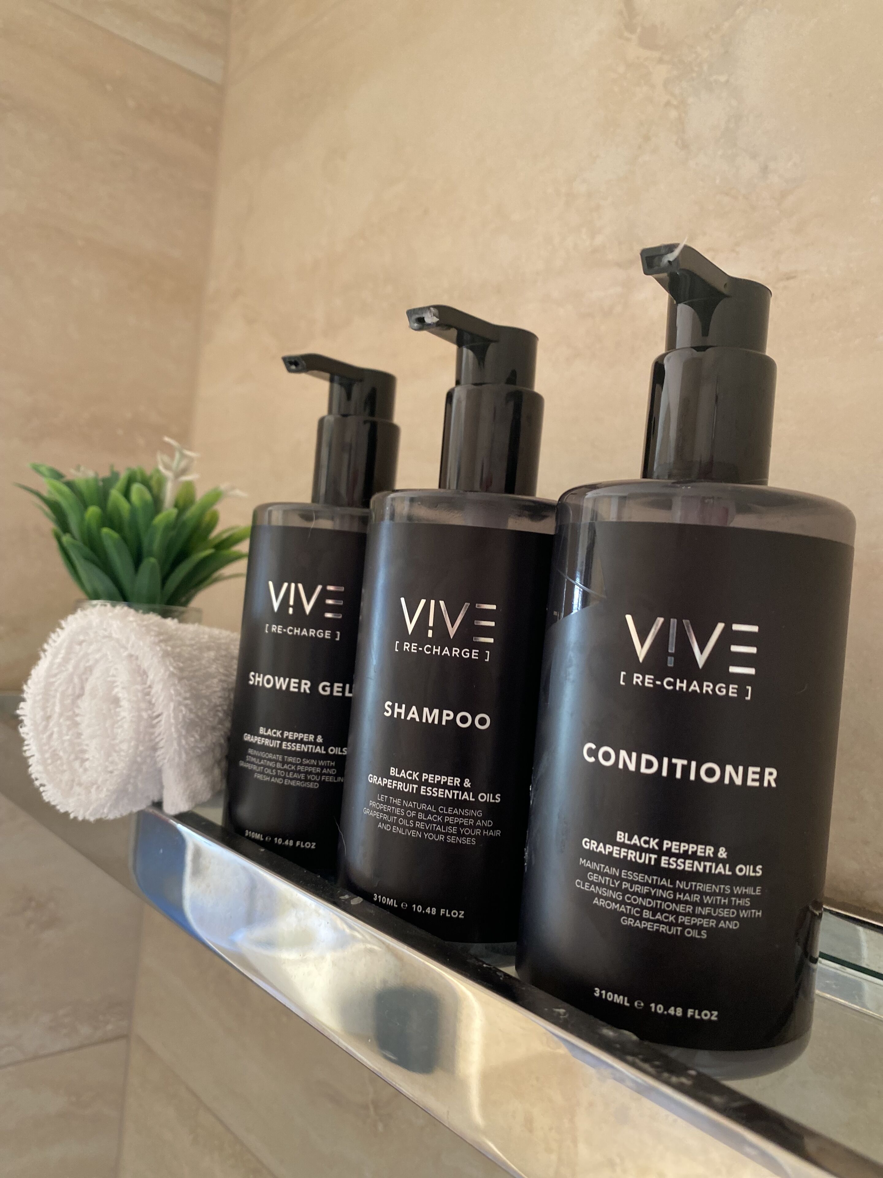 Trois produits de la gamme VIVE Re-Charge sont posés sur une étagère dans une salle de bain.
