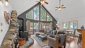 A spacious loft with a stone fireplace, large windows, and a cozy seating area. - Tranquil Tahoe A-Frame, Walk to Beach! (Tahoe Vista)
