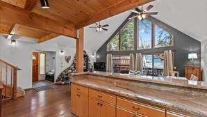 A spacious kitchen with wooden cabinets, a granite countertop, and a large window offering a view of the outdoors. - Tranquil Tahoe A-Frame, Walk to Beach! (Tahoe Vista)